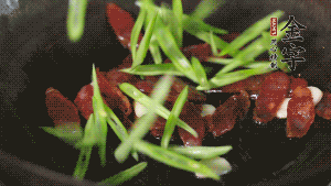 先后下香腸片、四季豆絲均勻翻炒，加適量清水燜煮一下。