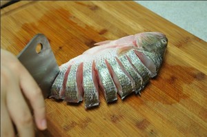 將鱸魚(yú)清洗干凈，從脊椎處切斷至腹部，腹部保留1cm左右不要切斷。