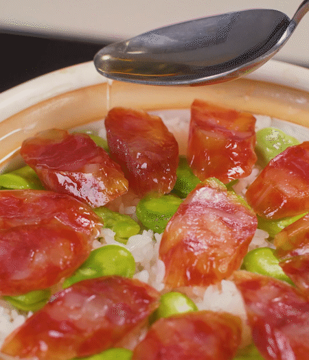 大米出現(xiàn)小孔時開蓋放香腸，往鍋邊淋入少許油，再燜煮8~10分鐘左右。