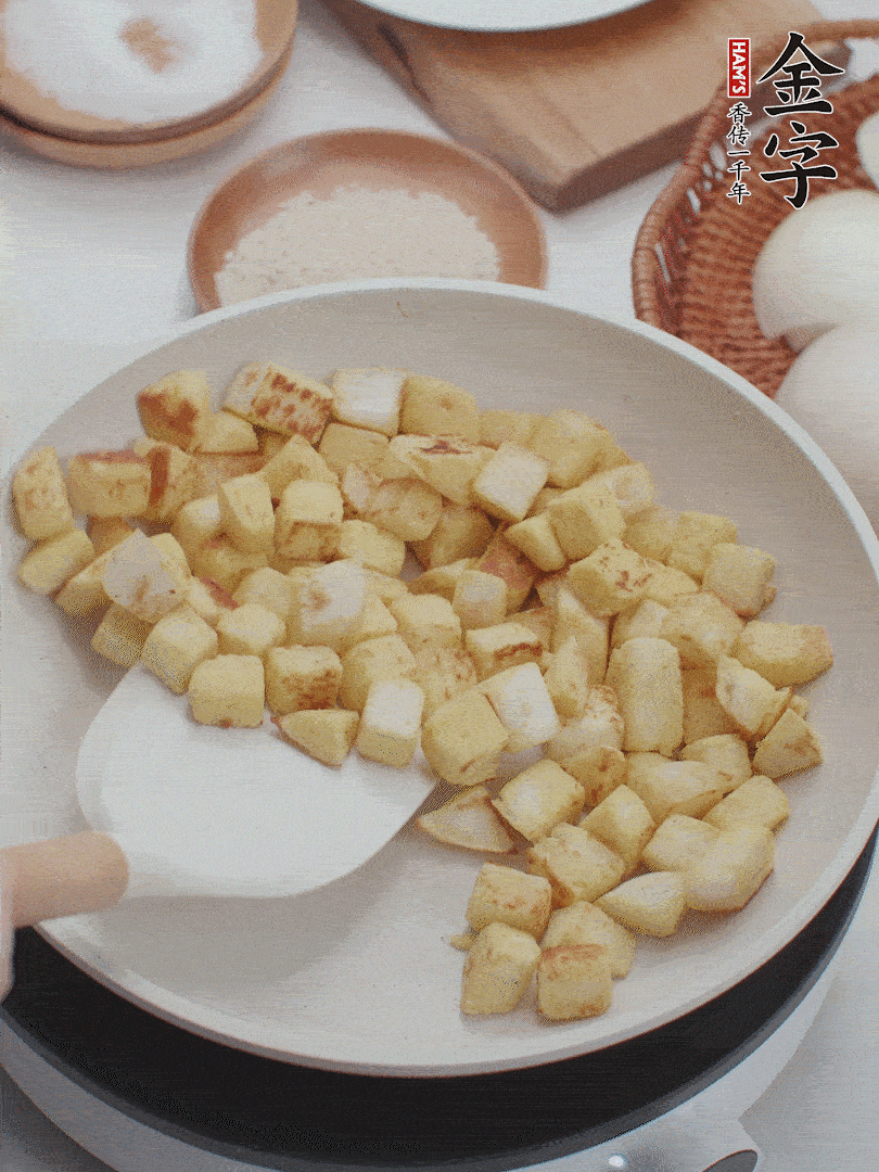 起鍋熱油，倒入饅頭丁，小火煎至蛋液凝固定型再翻面，饅頭丁部煎至金黃時(shí)盛起待用。