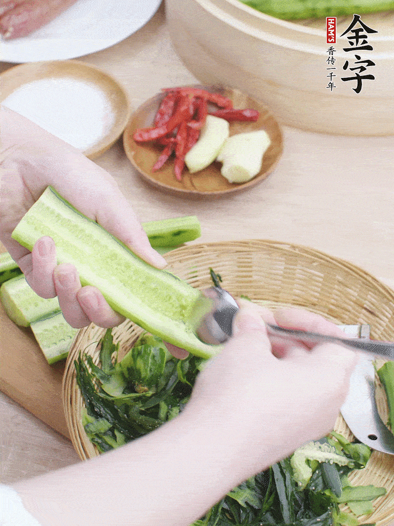 黃瓜削皮，對半切開，勺子挖去內(nèi)瓤，斜刀切片。青蒜斜刀切段。