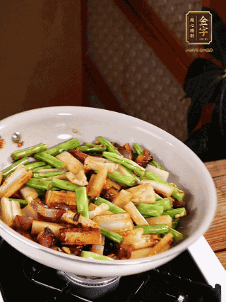 油熱下蒜末、干辣椒、醬肉煸炒出香味，依次下藕條、豆角翻炒均勻